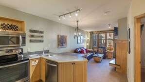 A modern kitchen with a central island, stainless steel appliances, and wooden cabinetry. - Silver Mill 8153 by Summit County Mountain Retreats (Keystone)