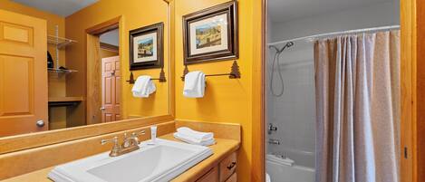 Un baño con lavamanos, espejo y cortina de ducha.