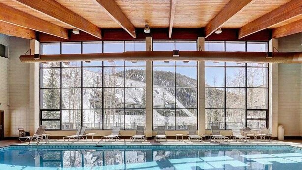 Una piscina con finestre illuminate dal sole e lettini da relax.