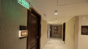 A hotel corridor with a fire exit sign, a door labeled '108', and a 'Fire' sign on the wall. - Best Western Darbar (New Delhi)