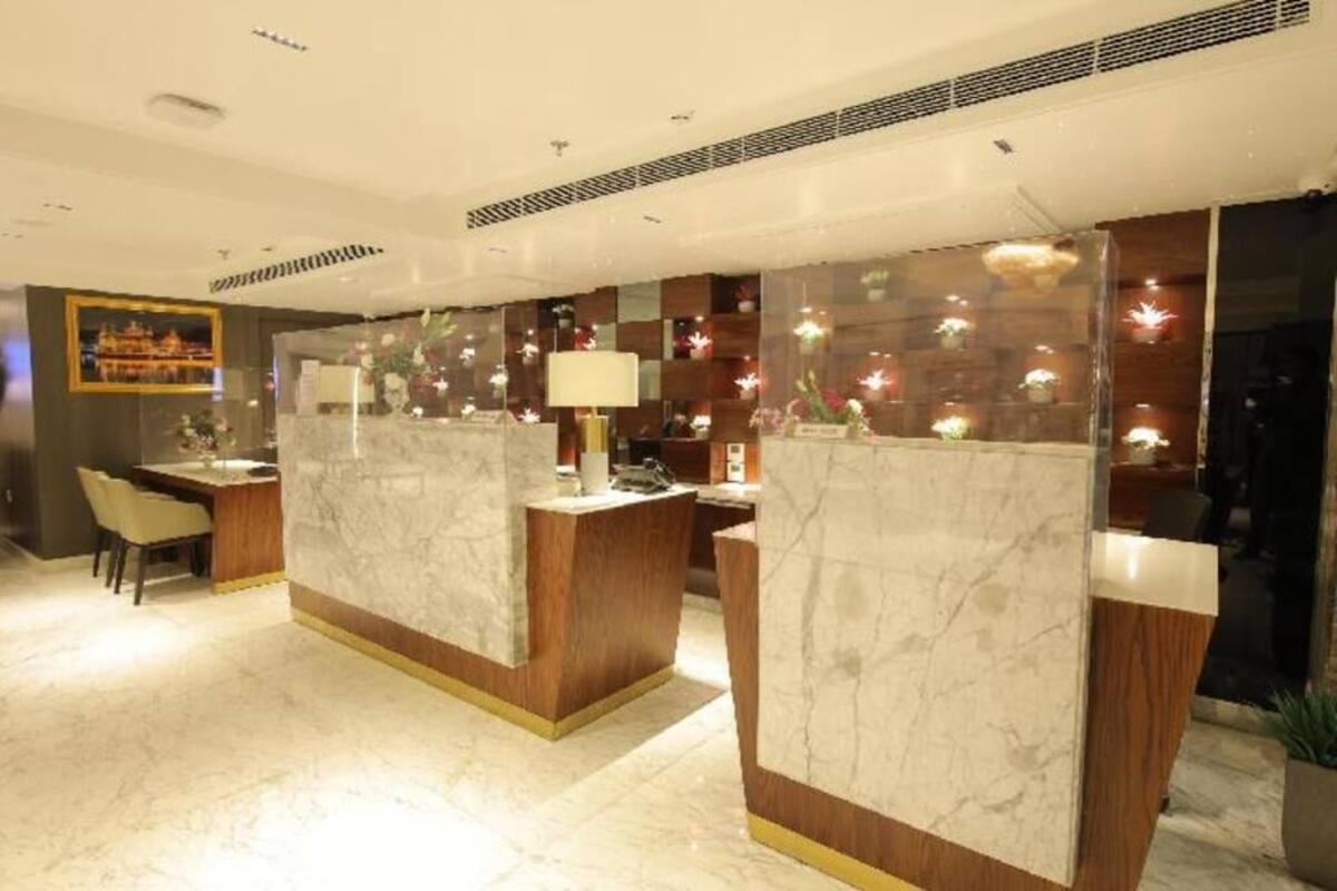 A reception area with marble counters, a desk, chairs, and a wall with decorative lights.