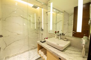 A modern bathroom with a large mirror, a marble sink, and a glass shower enclosure. - Best Western Darbar (New Delhi)