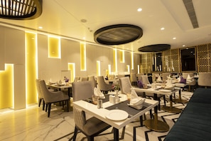 A modern dining area with multiple tables and chairs, equipped with place settings and ambient lighting. - Best Western Darbar (New Delhi)
