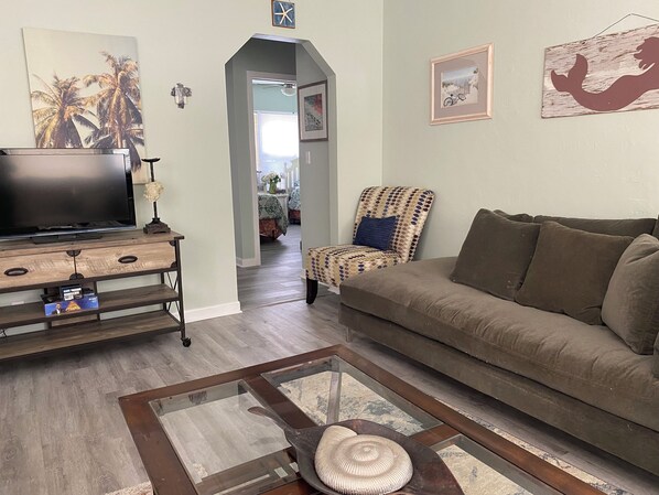 Una sala de estar con televisor, sofá, sillón estampado y una mesa de centro.