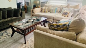 Una sala de estar con un sofá, sillones, una mesa de centro y una lámpara.