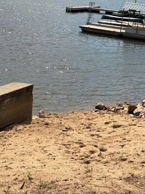 A sandy beach with a concrete structure and a dock extending into calm water. - Lakeside Paradise, NEW Boat Dock, Steps to Water, Canoe & Firepit (Butler)