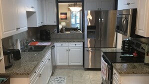 A modern kitchen with white cabinets, stainless steel appliances, and a granite countertop. - Pet Friendly Townhome Between Ocean Isle and Sunset Beach (Ocean Isle Beach)