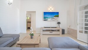A modern living room with a large TV, a wooden coffee table, and a grey sofa. - Villa Cacyli: private heated pool and Jacuzzi, view of Baie des Mulets (Le Vauclin)