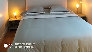A bedroom with a bed, two bedside lamps, a wall-mounted picture, and a woven ceiling light fixture. - Charming fisherman's cottage with terrace 6 minutes walk from the beach (Quiberon)
