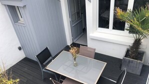 A patio with a glass table and chairs, a small potted plant, and a window with a view of the interior. - Charming fisherman's cottage with terrace 6 minutes walk from the beach (Quiberon)