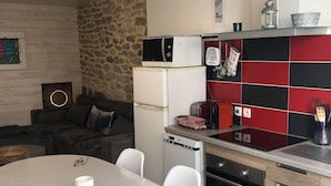 A compact kitchen with a dining area, a stone wall, and a modern design. - Charming fisherman's cottage with terrace 6 minutes walk from the beach (Quiberon)