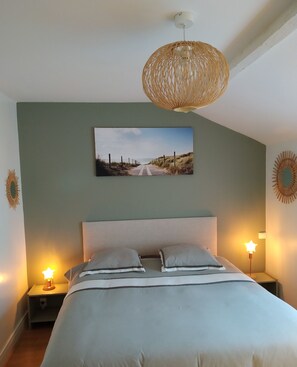 Ein Schlafzimmer mit einem Bett, zwei Nachttischlampen, einem Wandbild und einer gewebten Deckenleuchte.