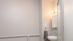 Une salle de bain comprenant des toilettes, un lavabo et un espace douche.
