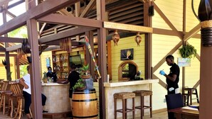 Une terrasse en bois avec un coin bar, des tabourets en bois et un grand tonneau en bois.
