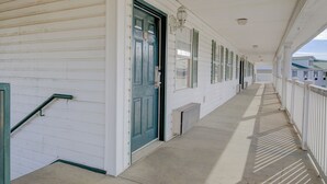 A covered corridor with white walls, a green door, and a white railing. - Plantation Inn & Suites Near Locust Grove I 75 (Jackson)