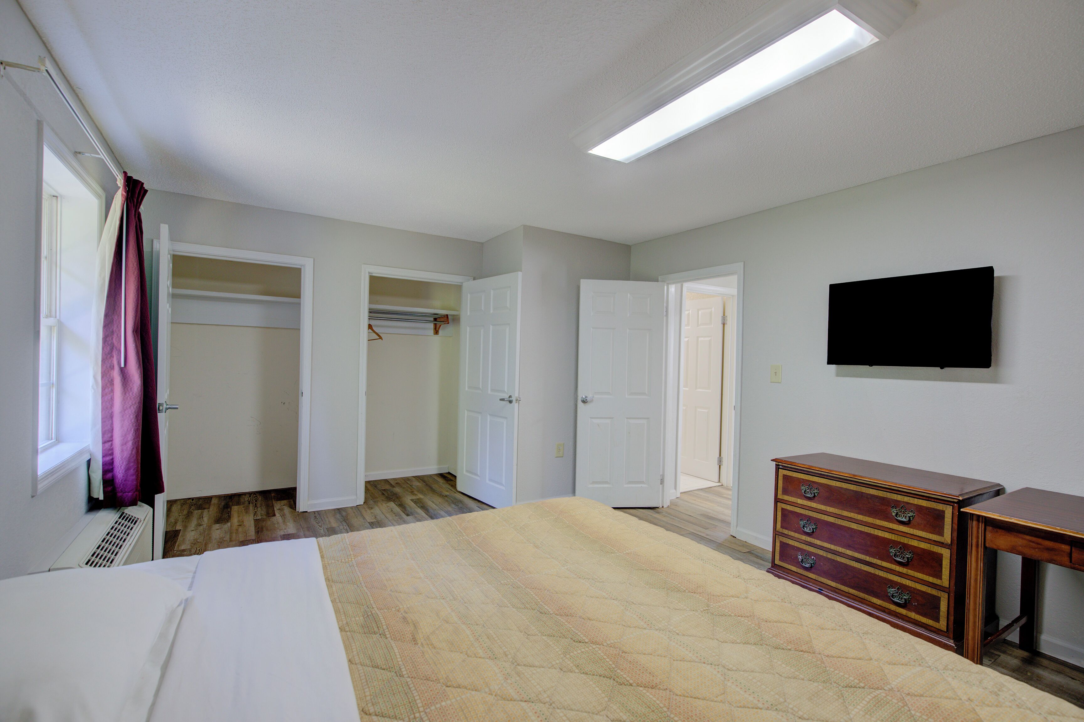 Ein Schlafzimmer mit einem Bett, einem Schminktisch, einem Fernseher und einem Kleiderschrank.