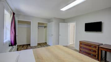 Ein Schlafzimmer mit einem Bett, einem Schminktisch, einem Fernseher und einem Kleiderschrank.