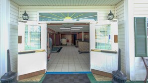 A hotel entrance with a sun motif above the doors, a tiled floor, and a central hallway leading to rooms. - Plantation Inn & Suites Near Locust Grove I 75 (Jackson)