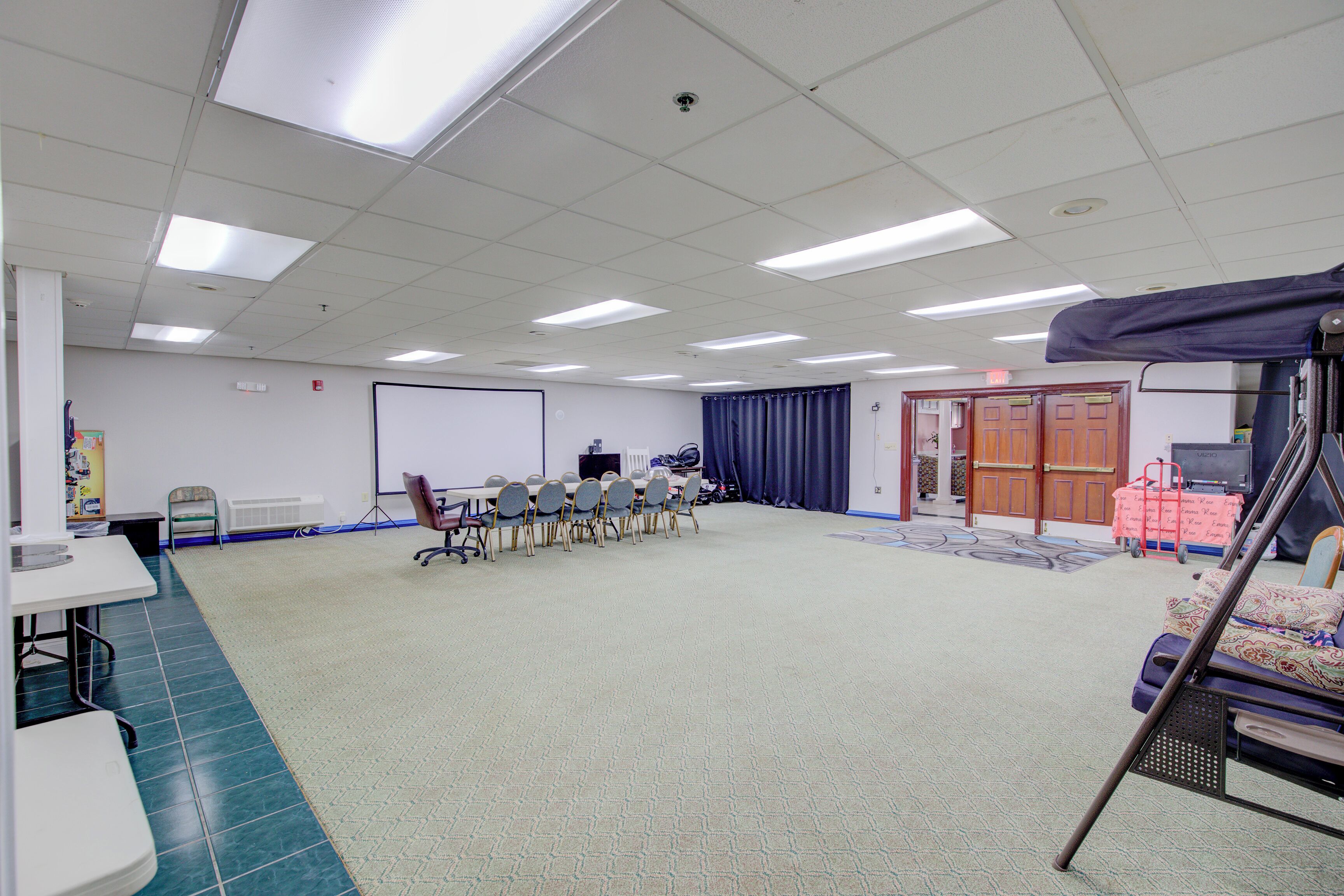 A conference room with a whiteboard, a projector, and a large screen. There are several chairs arranged around a table.