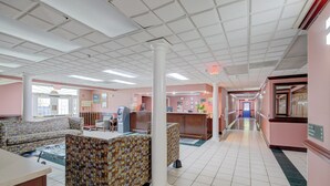 A lobby with a reception desk, seating area, and a hallway leading to other rooms. - Plantation Inn & Suites Near Locust Grove I 75 (Jackson)