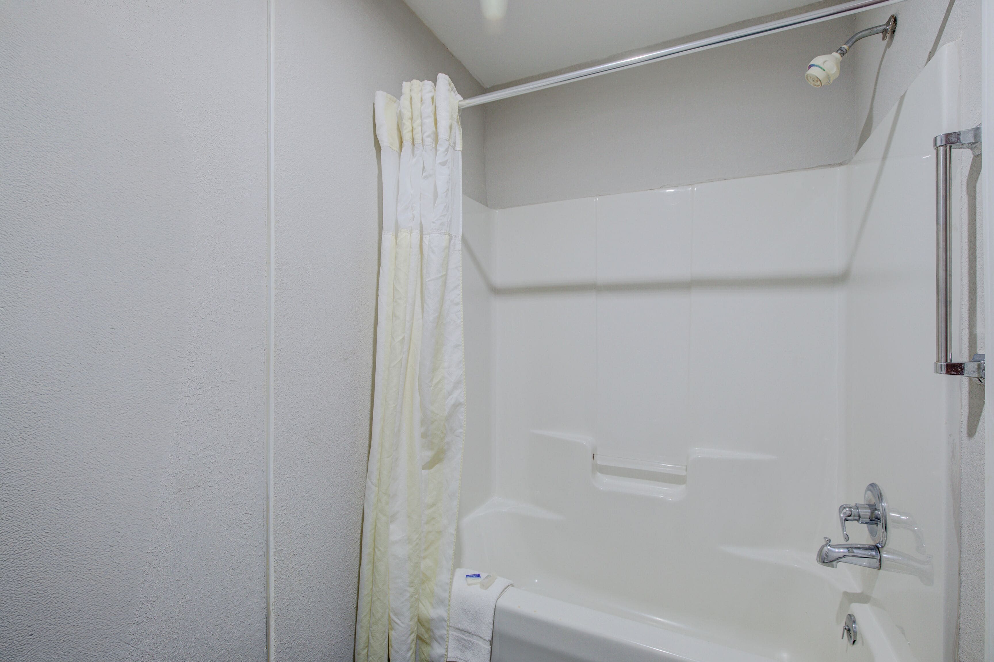 Eine weiße Badewanne mit Duschbrause und Handtuchhalter.
