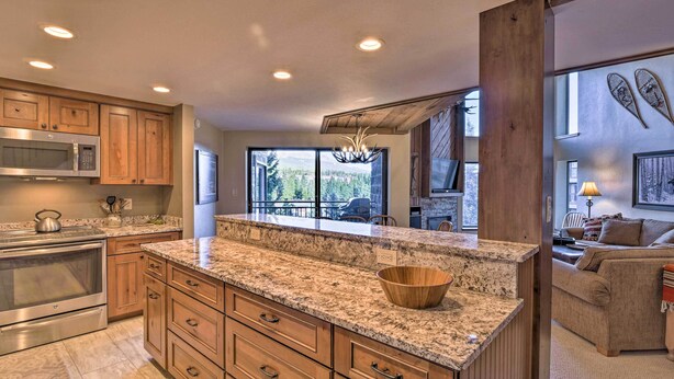 A kitchen with granite countertops, wooden cabinets, a built-in microwave, and a large island with a bowl. - Walk to Ski Lift: Mtn-View Condo in Breckenridge (Breckenridge)