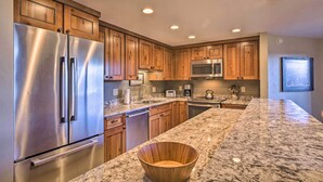 A modern kitchen with stainless steel appliances, wooden cabinets, granite countertops, and recessed ceiling lights. - Walk to Ski Lift: Mtn-View Condo in Breckenridge (Breckenridge)