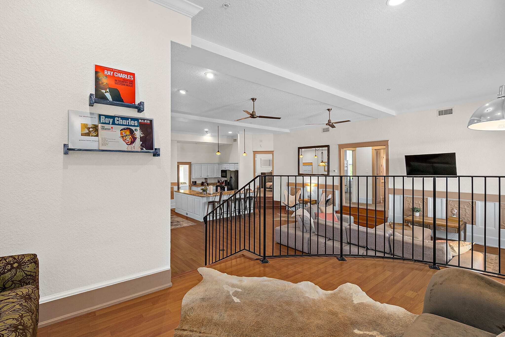 A modern living room with a sofa, a coffee table, and a fireplace. There is a staircase with a railing leading to an upper level.