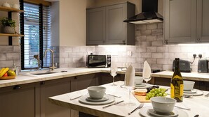 Une cuisine moderne dotée d’un plan de travail en marbre, de meubles gris, d’un four à micro-ondes encastré et d’un îlot central aménagé en coin repas.