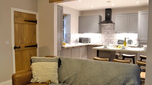 Un salon chaleureux avec un canapé en cuir, un plaid en tricot et une porte en bois.