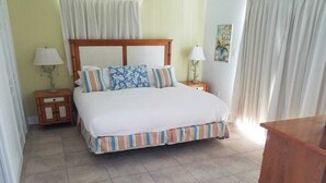 A neatly arranged bedroom with a large bed, two bedside tables, and a nightstand. - "Infinity Poolside" - Ocean Villa 2 BR / 3 BA  (Bimini)