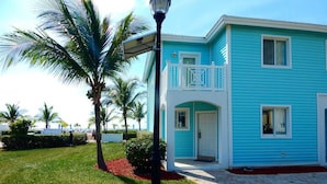 A two-story building with a balcony, surrounded by palm trees and a well-maintained lawn. - "Infinity Poolside" - Ocean Villa 2 BR / 3 BA  (Bimini)