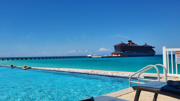 A pool with clear blue water, a lifeguard chair, and a distant cruise ship. - "Infinity Poolside" - Ocean Villa 2 BR / 3 BA  (Bimini)