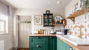 A kitchen with green cabinets, a wooden countertop, a white sink, and a backsplash with star patterns. - Peaceful Studio Flat With Patio and Dogs Allowed (Cobham)