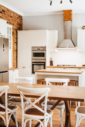 Eine moderne Küche mit weißen Schränken, einem Holztisch und Korbstühlen.