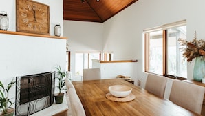 Un coin repas comprenant une table en bois, des chaises, un bol décoratif, une horloge murale et un vase contenant des fleurs séchées.