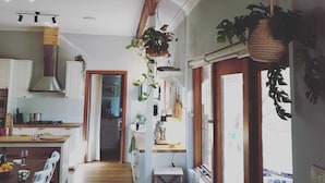 Une cuisine avec des poutres en bois, des meubles blancs et des plantes suspendues.