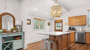 Une cuisine moderne avec des meubles en bois, un grand îlot central et un luminaire suspendu.