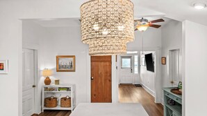 Une pièce spacieuse avec une grande table blanche, une porte en bois et un ventilateur de plafond.