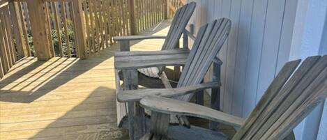 A wooden deck with Adirondack chairs and a railing.