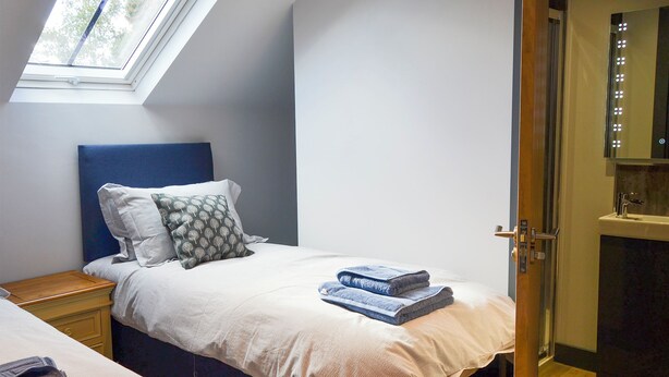 Une chambre à coucher comprenant un lit, une table de chevet, une fenêtre et une porte donnant sur une salle de bain.