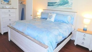 Un dormitorio con cama, mesitas de noche, cómoda y obras de arte en las paredes.