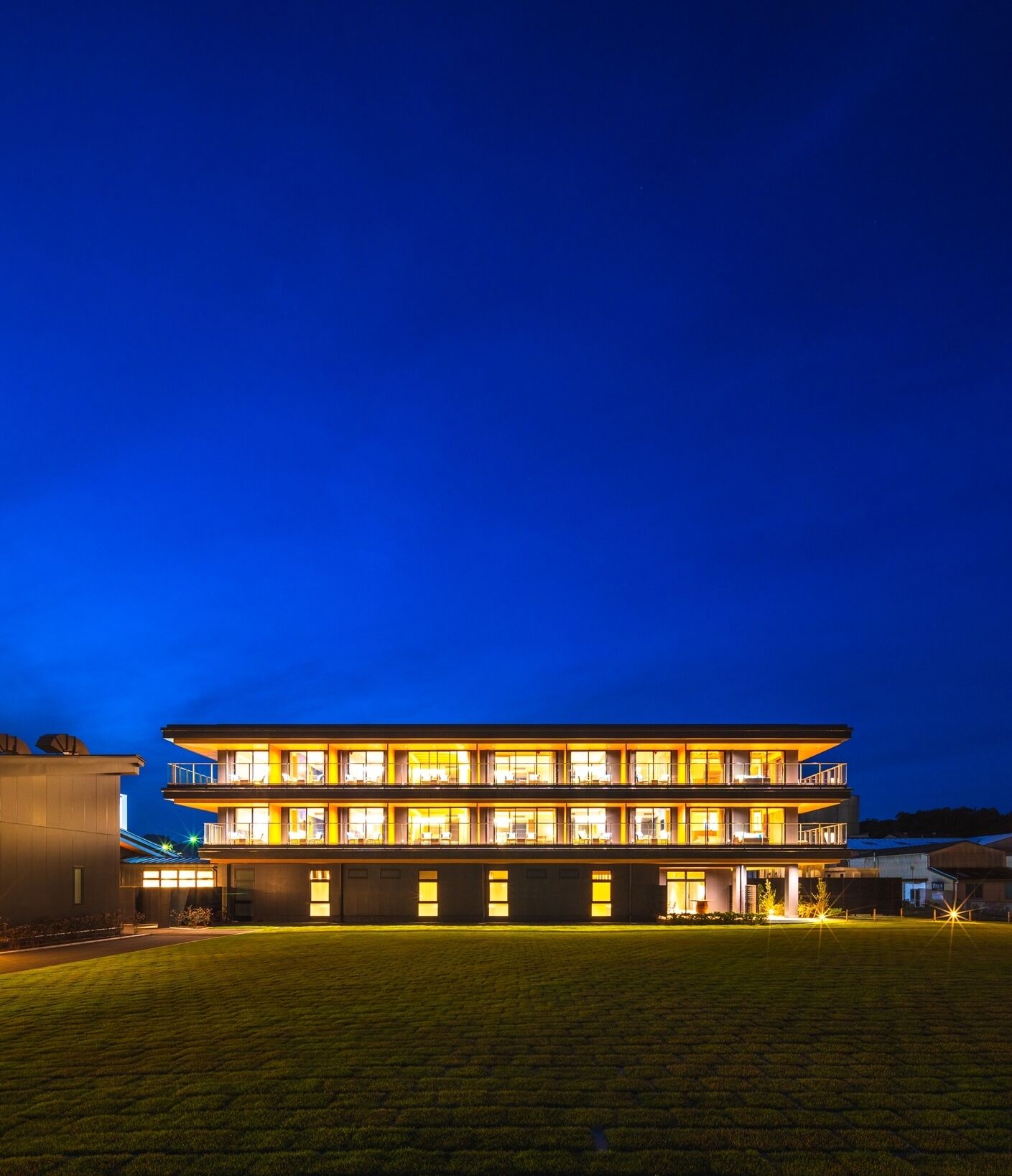 Un hotel a più piani con tetto piatto, ampie finestre e una facciata ben illuminata.