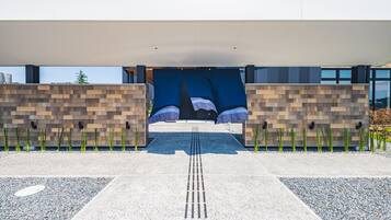 Entrada moderna de um edifício, com um caminho que leva a uma área coberta.
