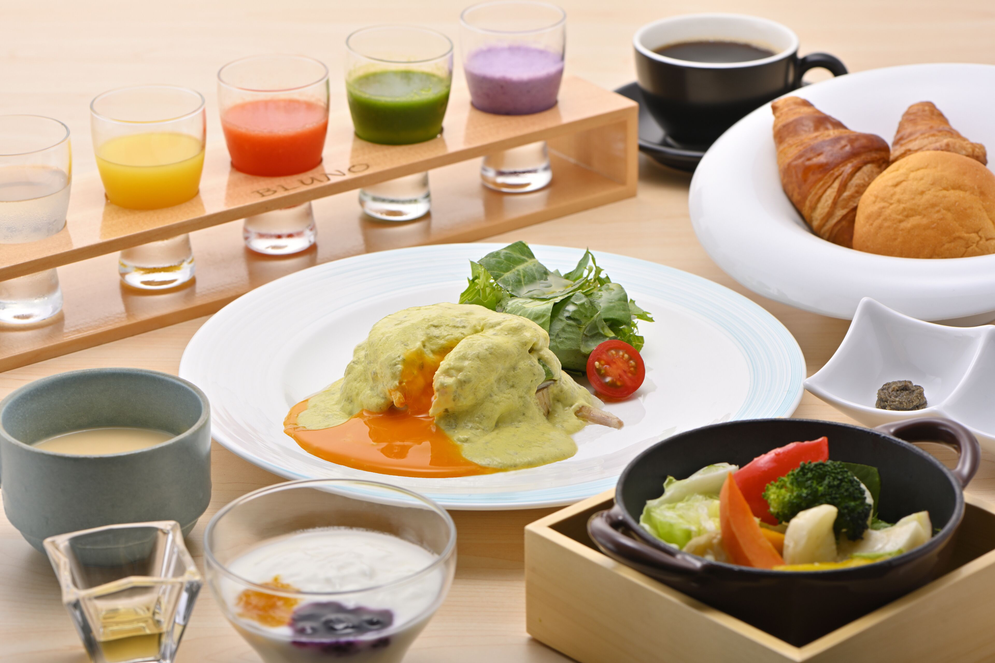 Une table dressée pour le petit-déjeuner, avec différents plats, boissons et un croissant.