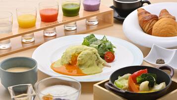 Une table dressée pour le petit-déjeuner, avec différents plats, boissons et un croissant.