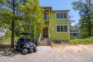 A two-story building with a green exterior, a wooden front door, and a sign that reads "Lemon Slough." A golf cart is parked in front.