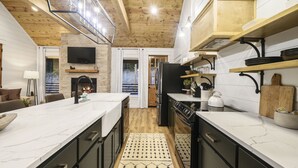 Una cocina moderna con una isla grande, electrodomésticos integrados y una chimenea de piedra.
