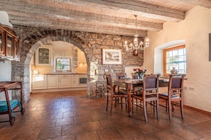 Una cocina rústica con paredes de piedra, armarios de madera y una zona de comedor con mesa y sillas.