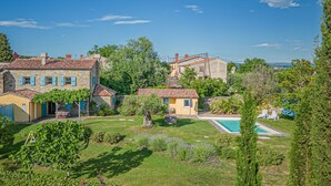 Une villa avec piscine, entourée de jardins luxuriants et d’arbres.